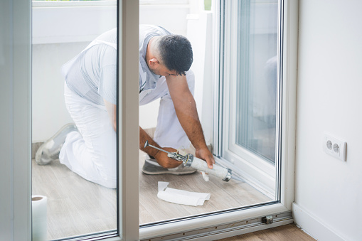 Construction worker working on a balcony and using a silicone sealant gun